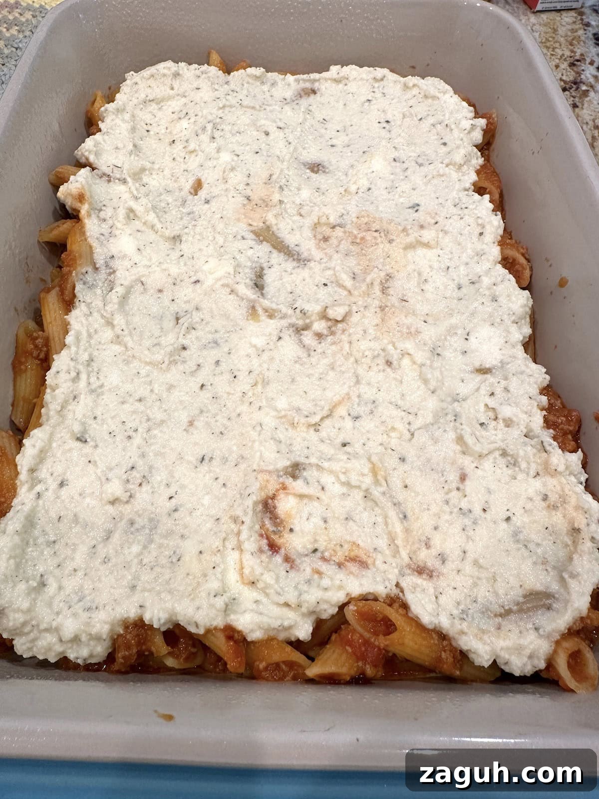 Quick No-Fuss Lasagna Recipe for Busy Weeknights 10 Ricotta cheese covered a layer of pasta, meat and cheese in a baking dish.