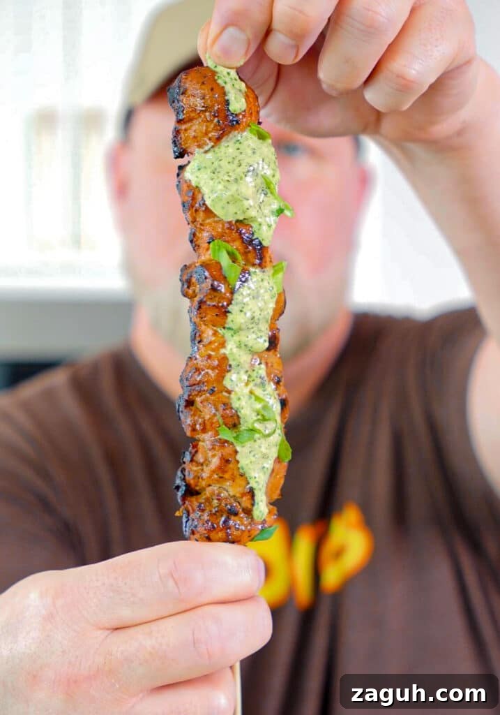 Peruvian-Style Chicken Breast Skewers with Aji Marinade 2 two hands holding a Peruvian chicken breast skewer with green sauce