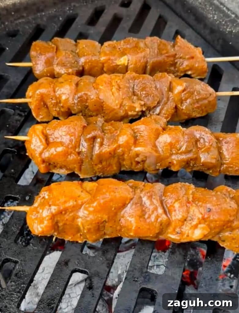 Peruvian-Style Chicken Breast Skewers with Aji Marinade 14 uncooked Peruvian chicken skewer being placed on a grill