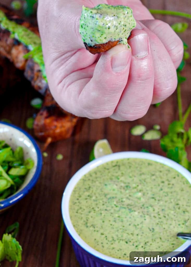 Peruvian-Style Chicken Breast Skewers with Aji Marinade 5 fingers holding a piece of Peruvian chicken dipped in green sauce