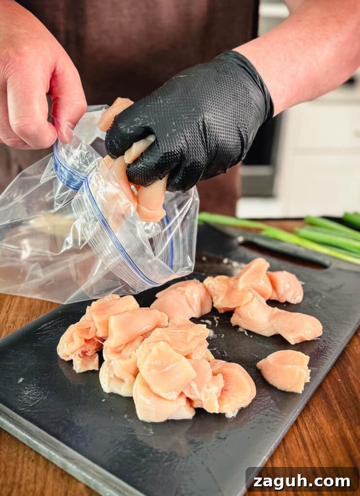 Peruvian-Style Chicken Breast Skewers with Aji Marinade 7 chicken breast cubes being added to a plastic bag