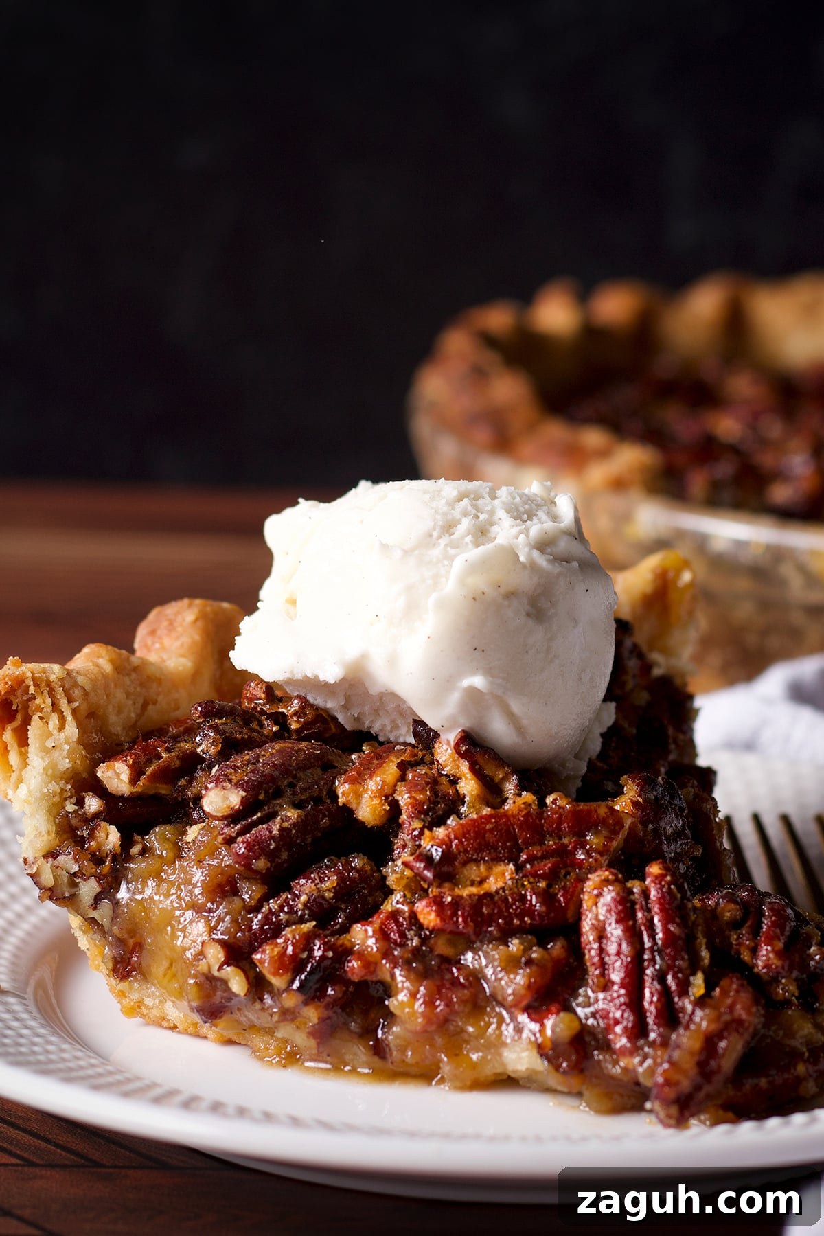 Pecan Pie Made Without Corn Syrup — Classic Recipe with Pure Maple 2 A slice of pecan pie topped with a scoop of vanilla ice cream.