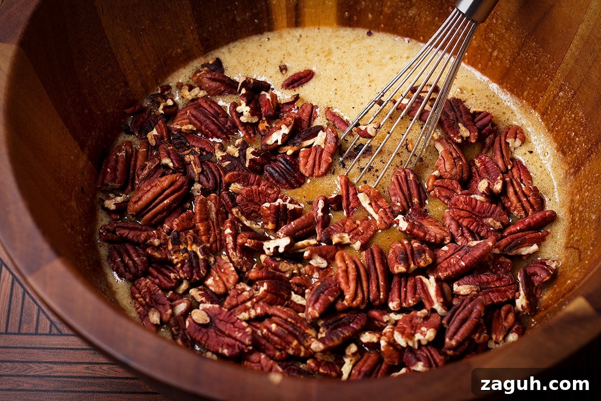 Pecan Pie Made Without Corn Syrup — Classic Recipe with Pure Maple 12 Someone using a wire whisk to stir toasted pecans into the other ingredients for pecan pie filling.