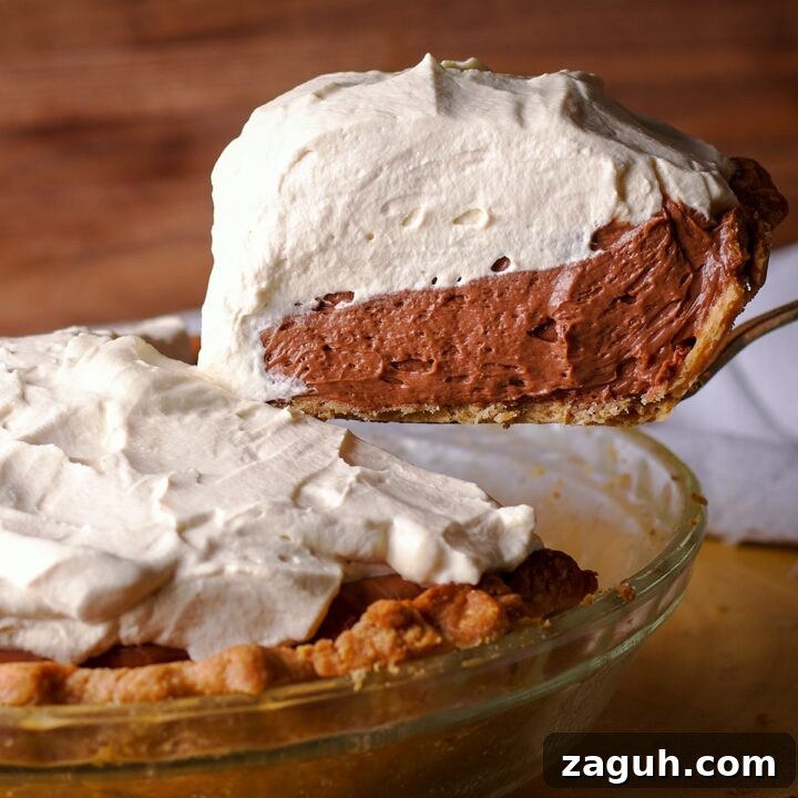 Someone using a spatula to lift a slice of chocolate cream pie.