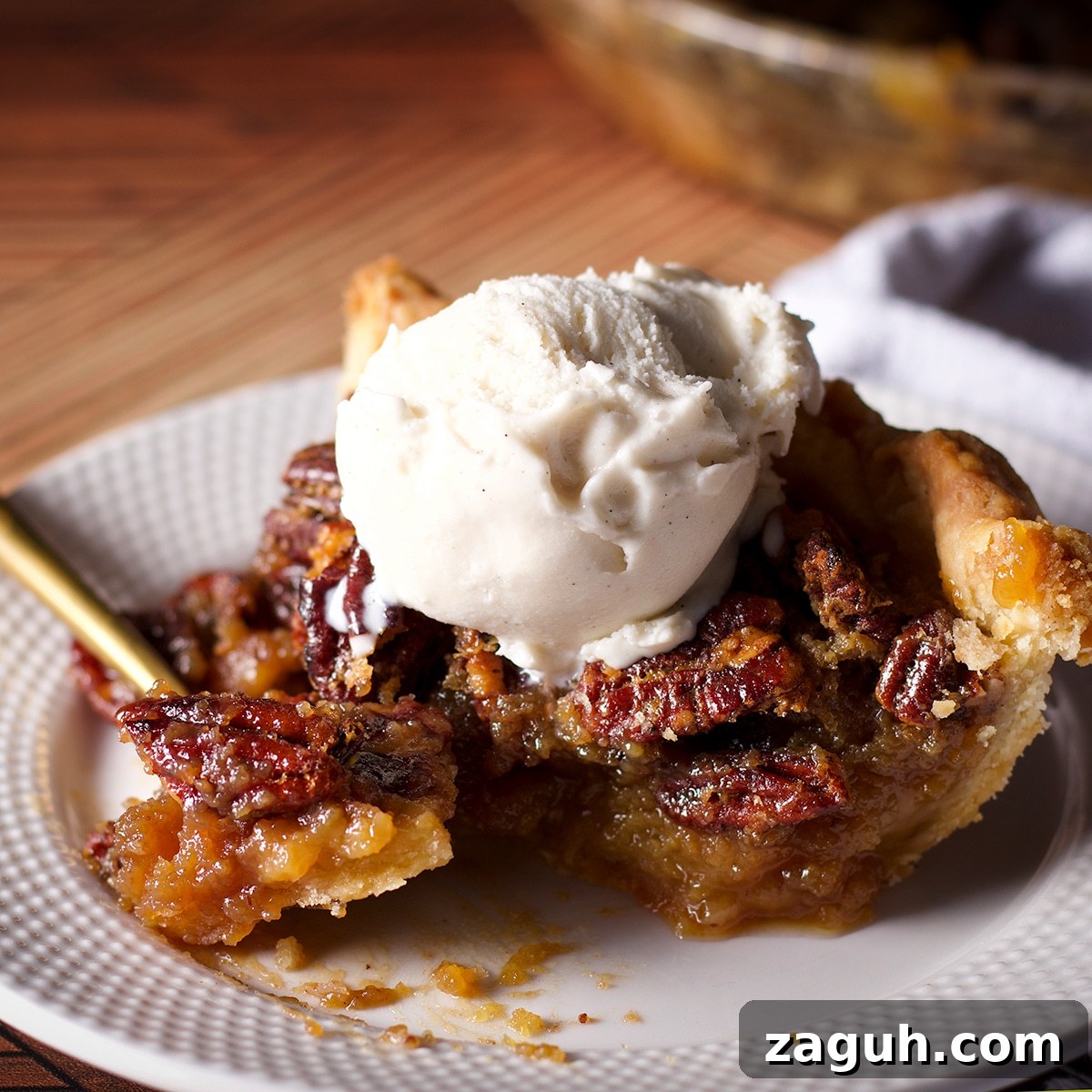 Pecan Pie Made Without Corn Syrup — Classic Recipe with Pure Maple 24 Someone using a gold fork to cut a bite of pecan pie from a slice.
