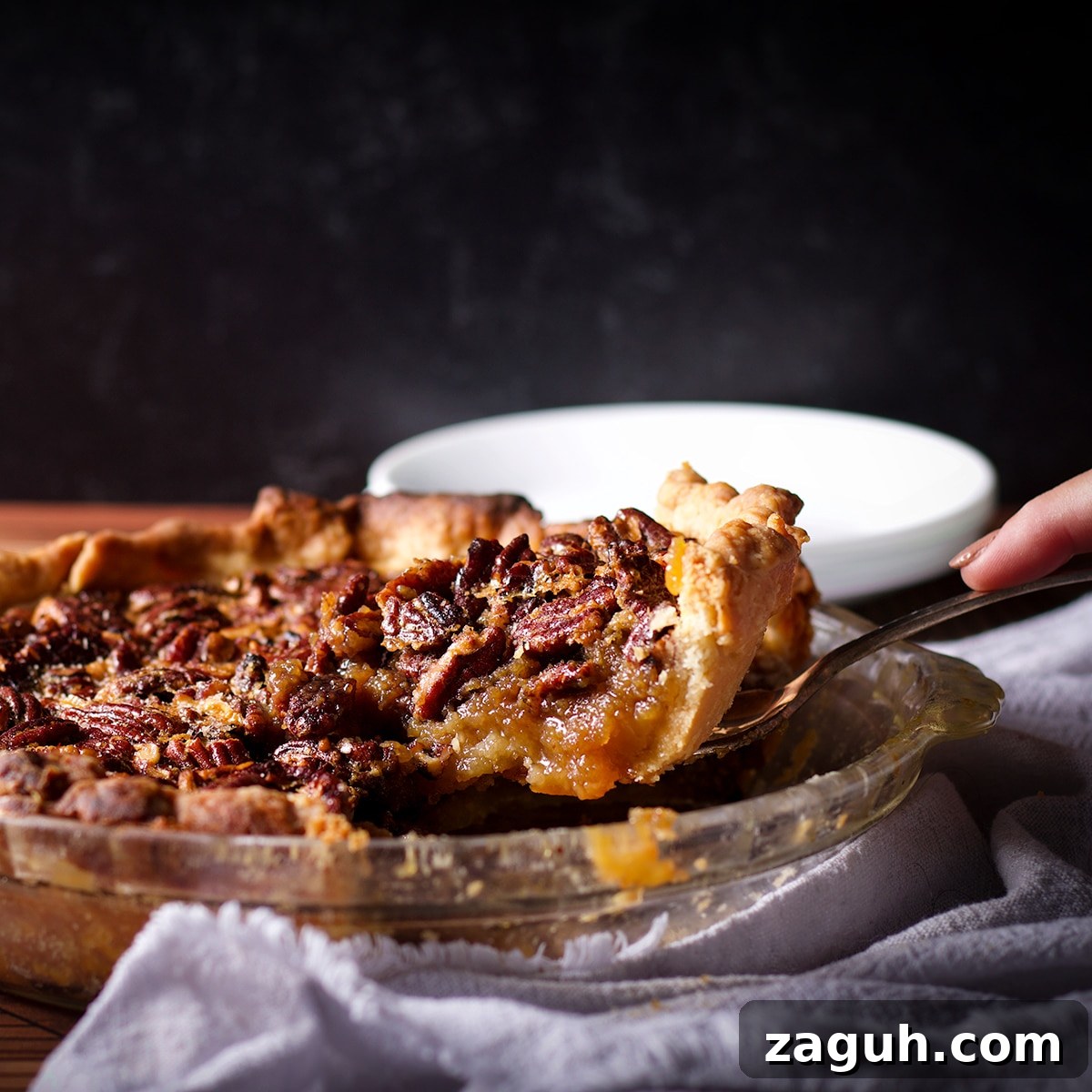 Pecan Pie Made Without Corn Syrup — Classic Recipe with Pure Maple 4 Someone using a pie server to serve a slice of pecan pie.