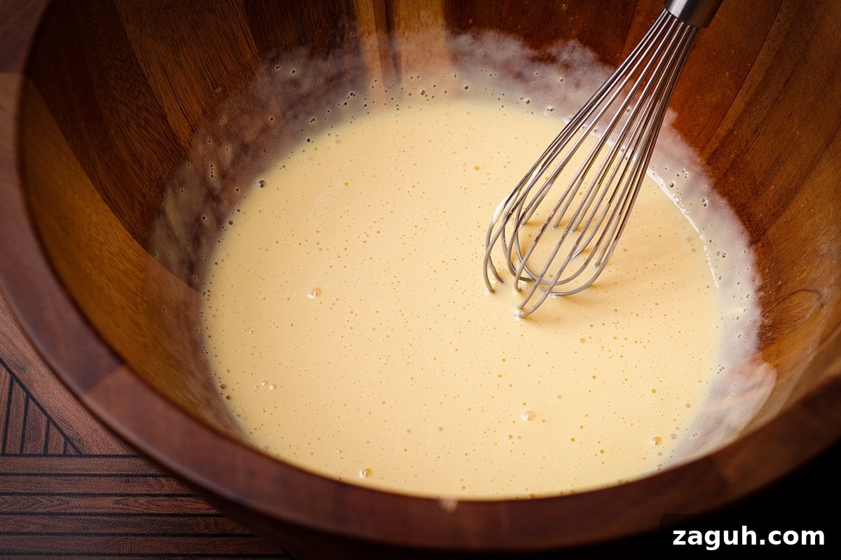 Pecan Pie Made Without Corn Syrup — Classic Recipe with Pure Maple 9 Someone using a wire whisk to blend sour cream into egg yolks.