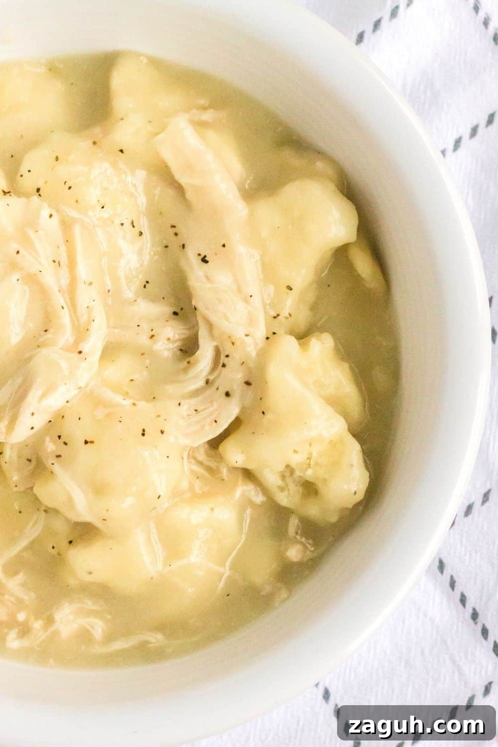 Slow-Cooker Chicken and Dumplings Recipe for Comforting Dinners 3 overhead view of a white bowl filled with homemade slow cooker chicken and dumplings