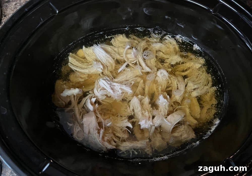 Slow-Cooker Chicken and Dumplings Recipe for Comforting Dinners 6 shredded chicken added to broth in a Crock Pot