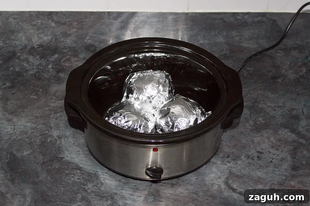 Slow Cooker Jacket Potatoes: Creamy Baked Potatoes Made Ahead 14 jacket potatoes wrapped in foil in a slow cooker