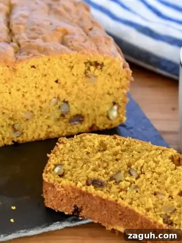 Pumpkin Walnut Raisin Bread on a cutting board with a cup of coffee.