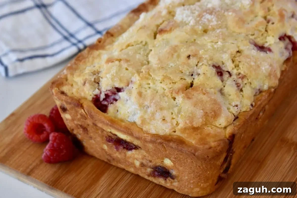 Lemon Raspberry Ricotta Loaf Cake Recipe 3 Lemon Raspberry Loaf on a wood cutting board with raspberries next it.