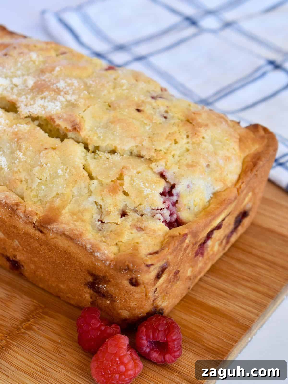 Lemon Raspberry Ricotta Loaf Cake Recipe 6 Lemon raspberry loaf cake on a wood cutting board with lemon sugar on top.