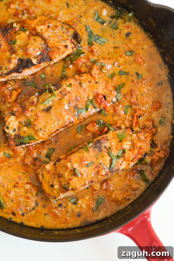 Marry Me Salmon Recipe: Creamy Garlic Butter Salmon You'll Love 12 flat lay shot of a red-handled skillet with 3 marry me salmon fillets in creamy sun dried tomato sauce.