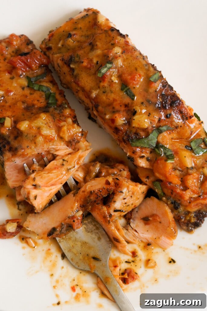 Marry Me Salmon Recipe: Creamy Garlic Butter Salmon You'll Love 13 silver forkful of marry me salmon on a white plate.