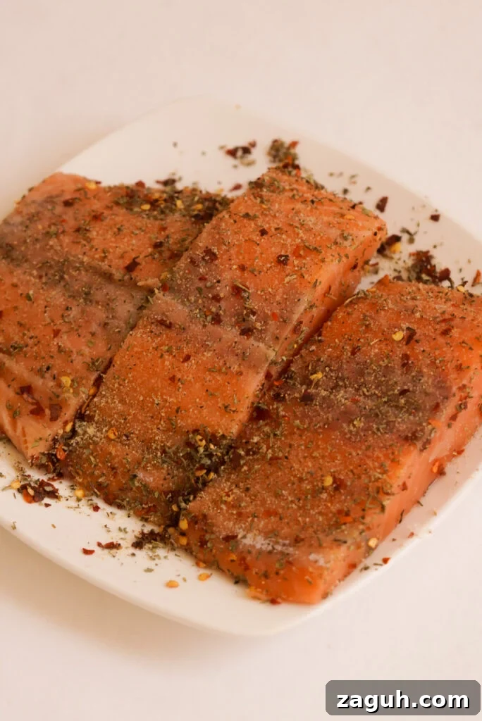 Marry Me Salmon Recipe: Creamy Garlic Butter Salmon You'll Love 6 3 salmon fillets on a square white plate with seasoning added.