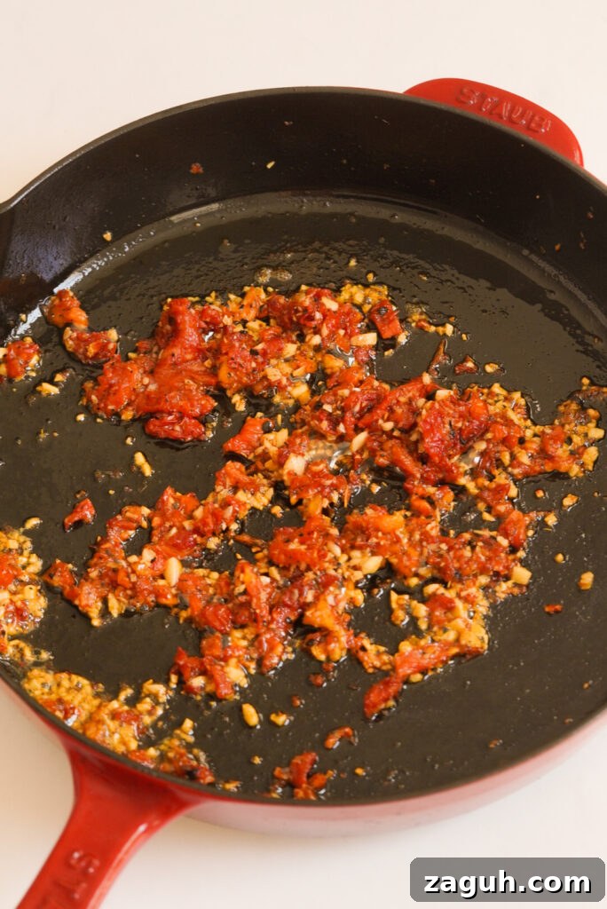 Marry Me Salmon Recipe: Creamy Garlic Butter Salmon You'll Love 8 sun dried tomatoes and garlic sauteing in a red staub skillet.