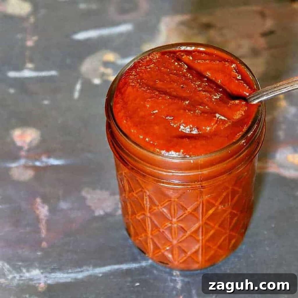 A jar of ketchup with a spoon in it.