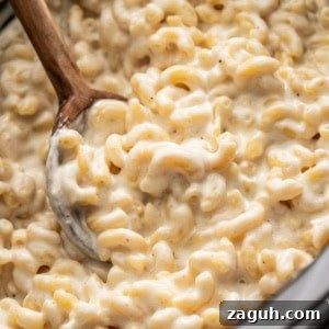 Creamy Slow Cooker Mac and Cheese with Cream Cheese 11 Creamy mac and cheese in a crockpot with a wood spoon scooping it out.