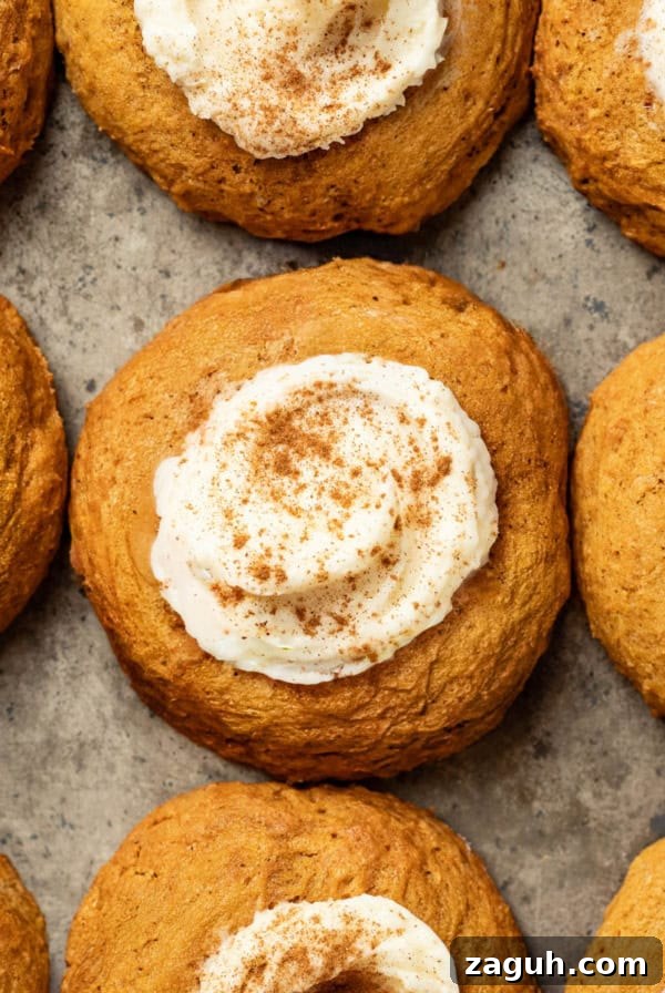 A baking sheet with pumpkin cookies topped with cream cheese frosting and cinnamon.