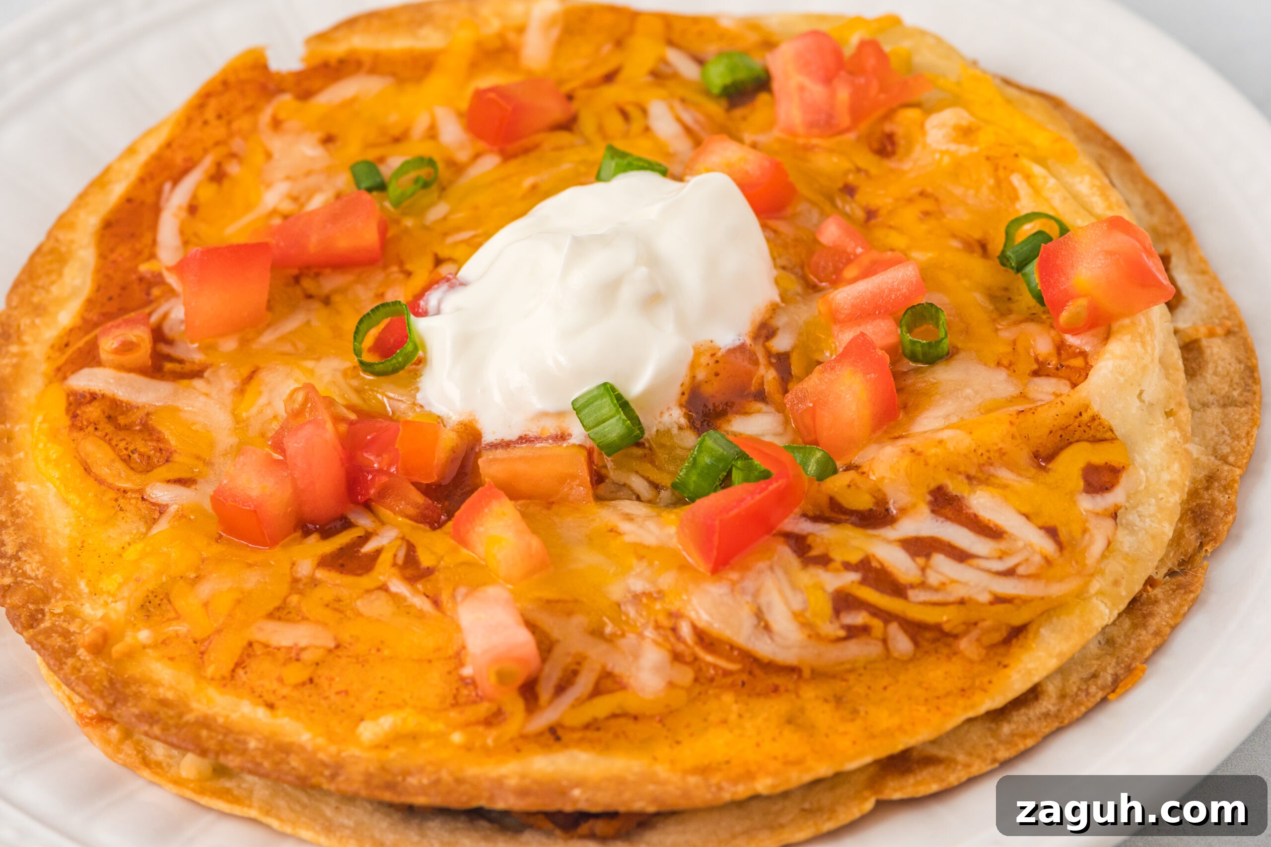 Taco Bell Mexican Pizza: How to Order, Ingredients & Nutrition Facts 12 Up close photo of a mexican pizza topped with sour cream, tomatoes and green onions
