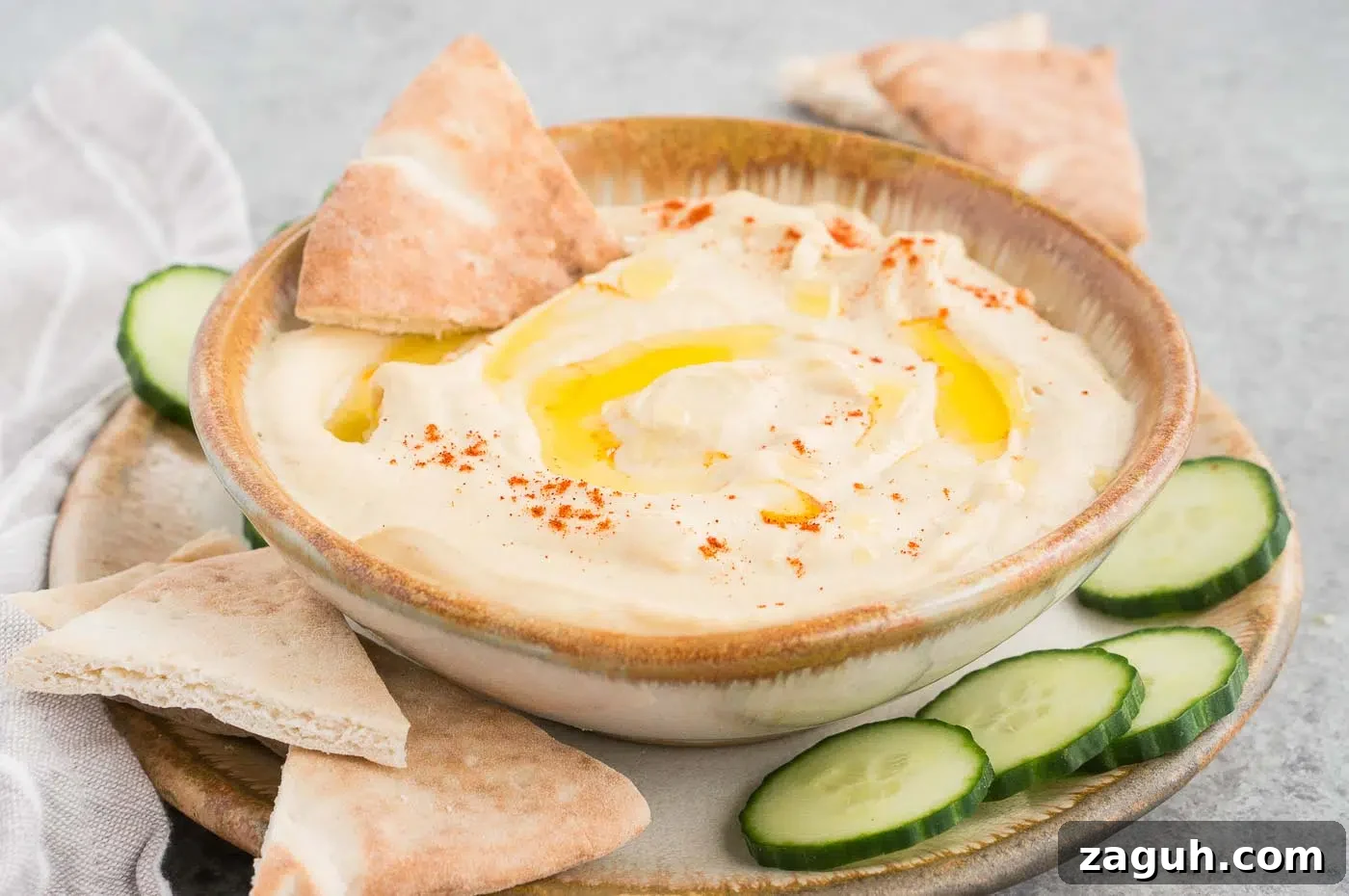 Creamy Homemade Hummus Recipe: Simple Chickpea Dip Tutorial 3 authentic hummus made at home served in a bowl with cucumber and pitas