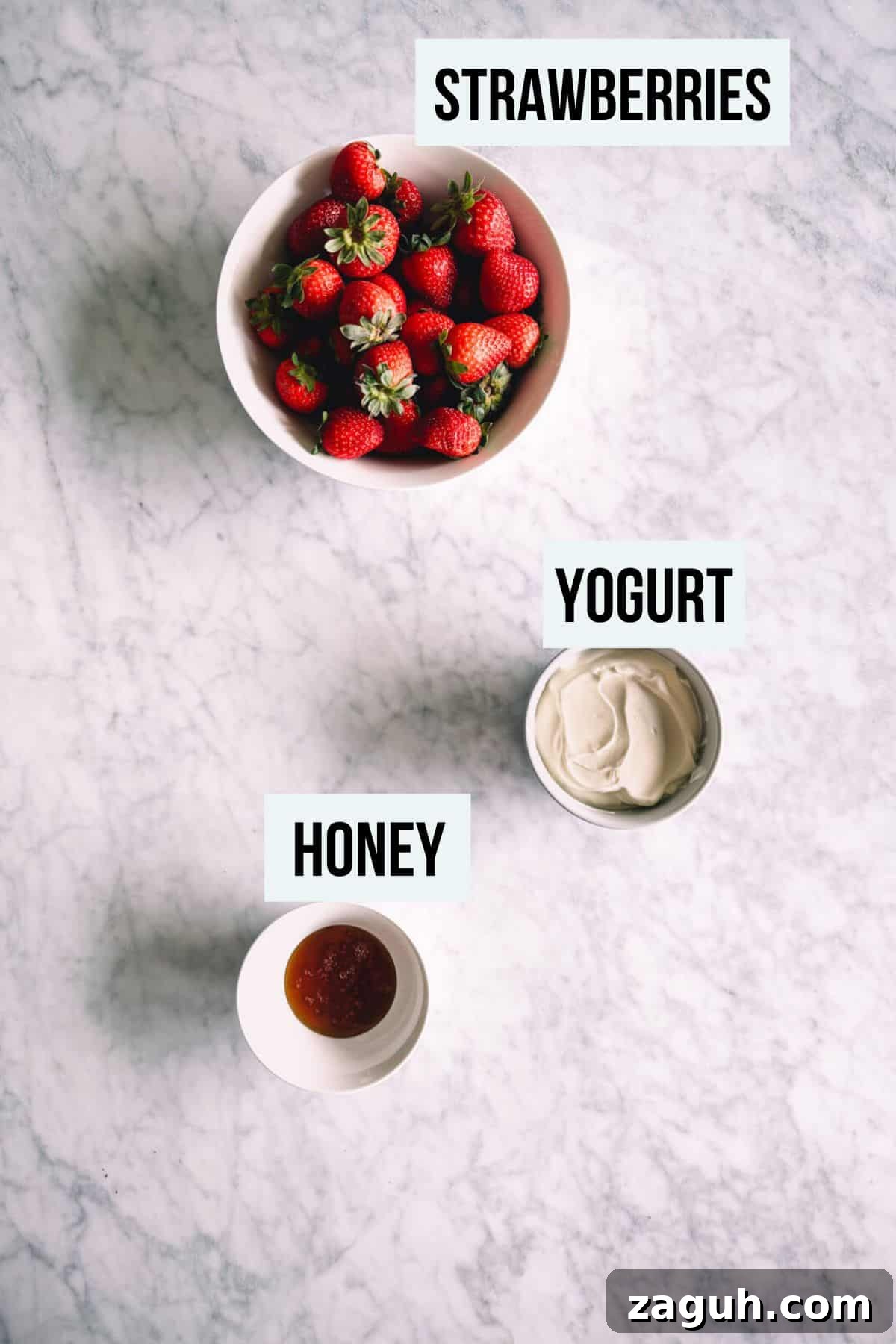 Strawberry Greek Yogurt Popsicles Recipe — Creamy Frozen Treats 3 the ingredients to make strawberry popsicles on a white marble table.