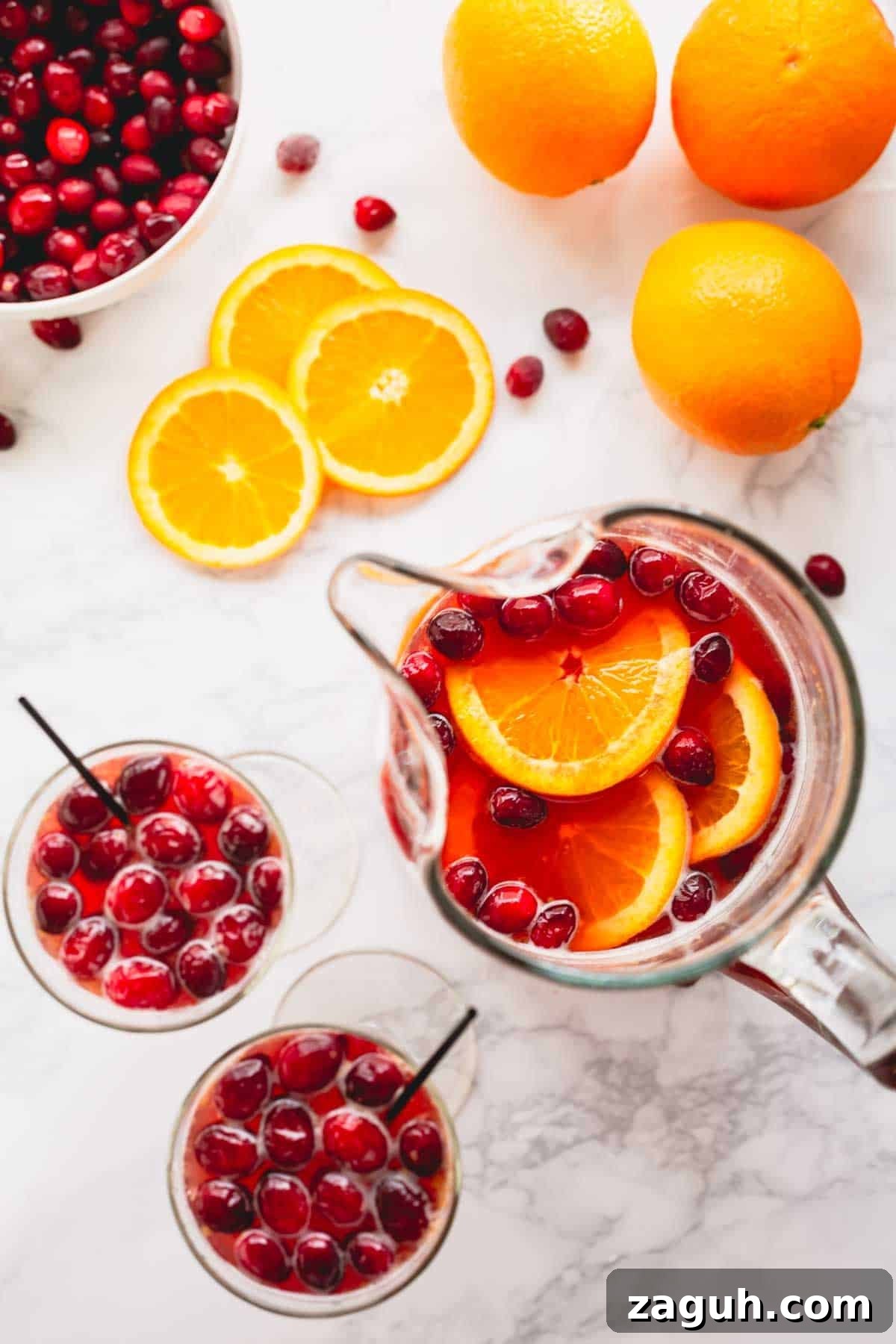 Sparkling Orange Cranberry Spritzer Recipe for Holiday Parties 7 Overhead image of two glasses of orange cranberry spritzer next to a pitcher of the drink mix.