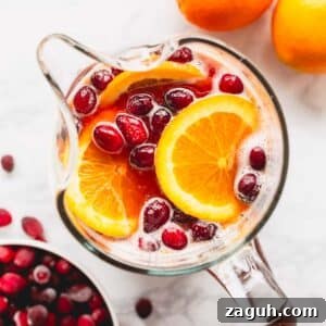 Sparkling Orange Cranberry Spritzer Recipe for Holiday Parties 10 Overhead image of a pitcher of orange cranberry spritzer with pomegranates and orange slices.