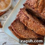 one loaf of applesauce bread on white plate with applesauce in bowl