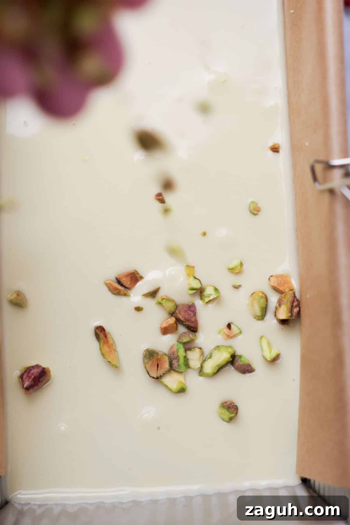 Homemade Pistachio Protein Bars Recipe for High-Energy Snacks 8 Chopped pistachios and dried rose petals being sprinkled onto white chocolate layer