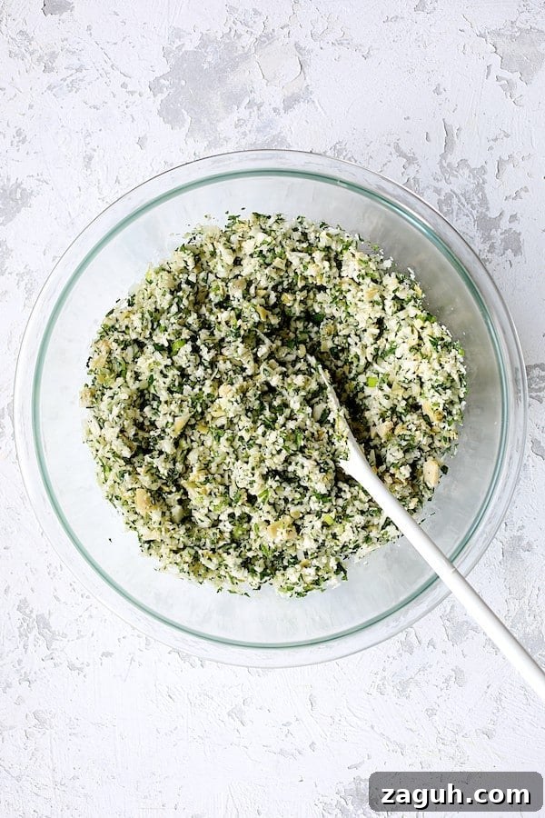 Cauliflower & Artichoke Tabbouleh: Fresh Low-Carb Salad Recipe 4 Photo of Cauliflower Artichoke Tabbouleh after ingredients are stirred together with white spoon.