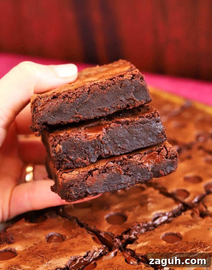 Chewy Sheet-Pan Brownies: One-Pan Recipe for Fudgy Bars 7 fudgy sheet pan brownies stacked in hand