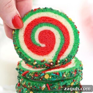 DIY Oreo Cookie Christmas Ornaments: Festive Homemade Ideas 11 Hand with red fingernail lifting up a Christmas Pinwheel Cookie from a stack of cookies.