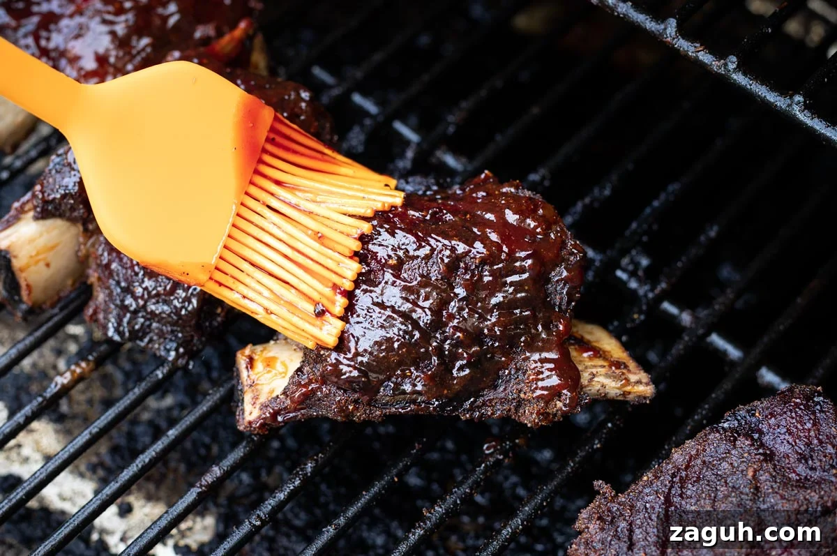Perfectly Smoked Beef Short Ribs: Tender BBQ Recipe 13 Basting BBQ sauce on ribs.