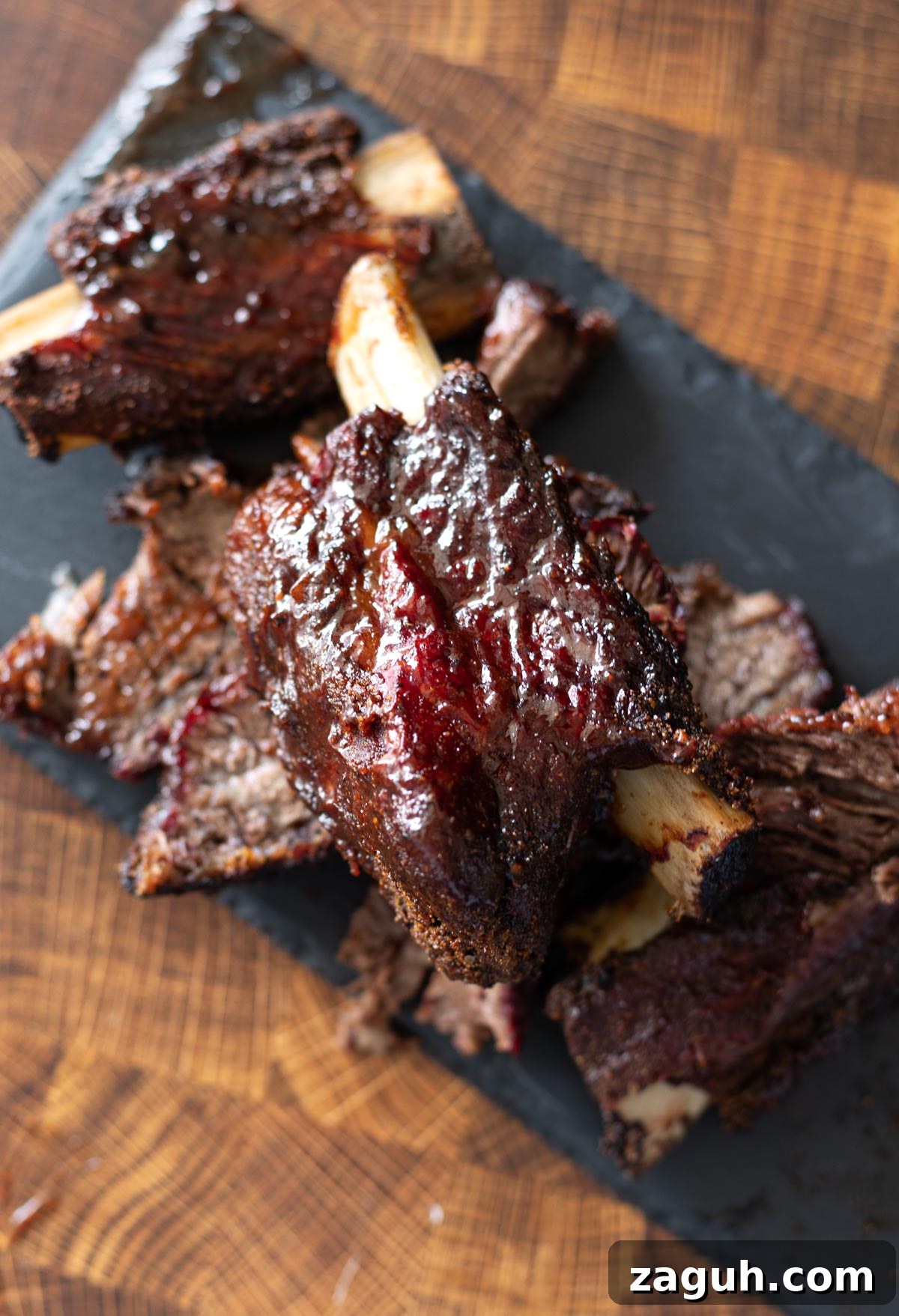 Perfectly Smoked Beef Short Ribs: Tender BBQ Recipe 4 Stacked smoked beef short ribs on a cutting board.