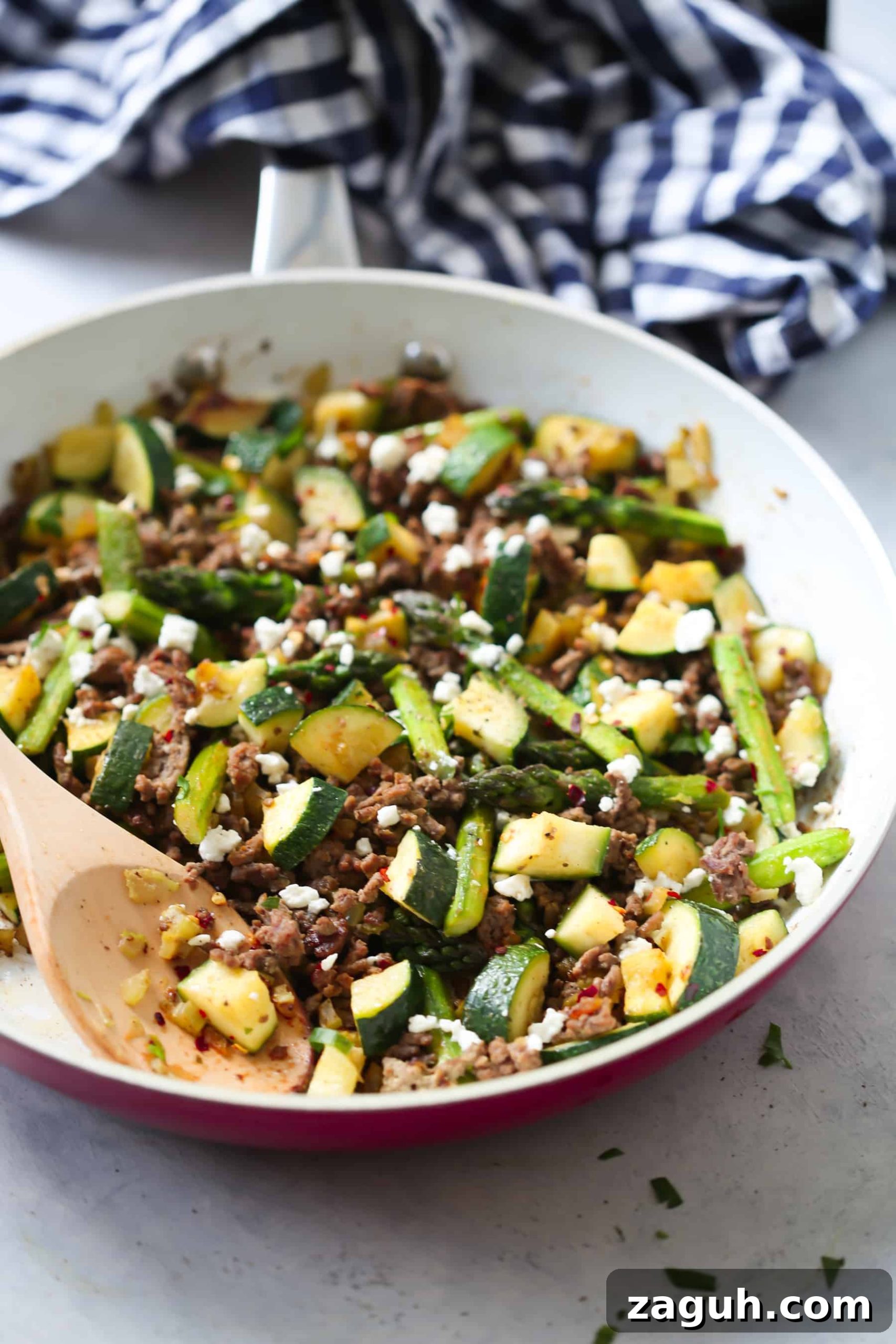15 Whole30 Meal-Prep Recipes for Stress-Free Weekly Planning 13 Ground beef veggie skillet in a white pan with a wooden spoon stirring the ingredients.