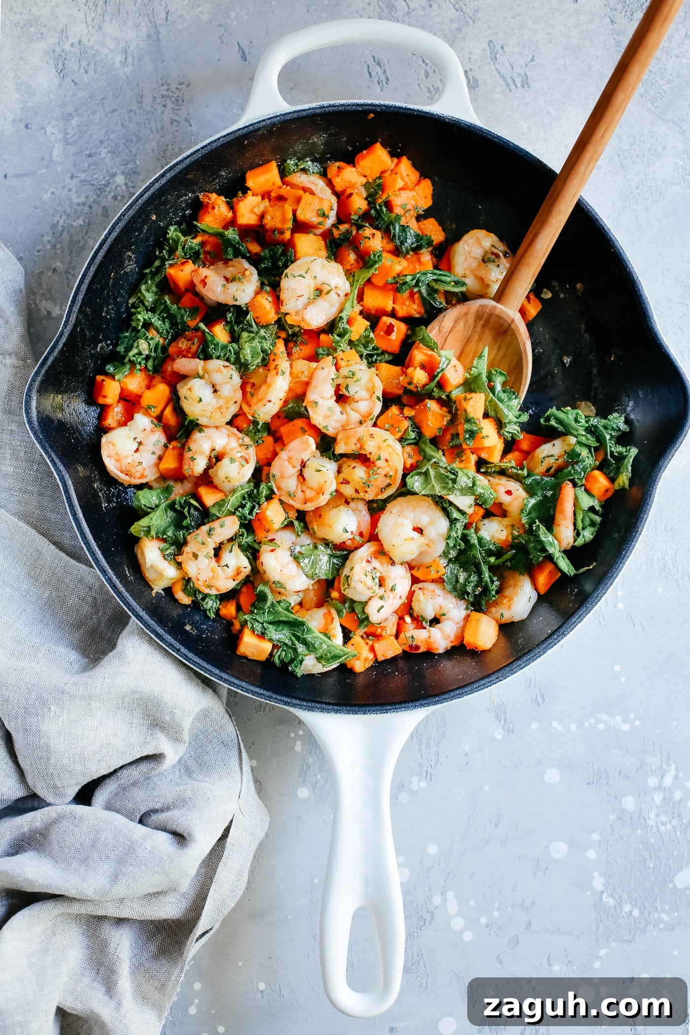 15 Whole30 Meal-Prep Recipes for Stress-Free Weekly Planning 14 An overhead view of a white skillet containing shrimp, sweet potato and kale.