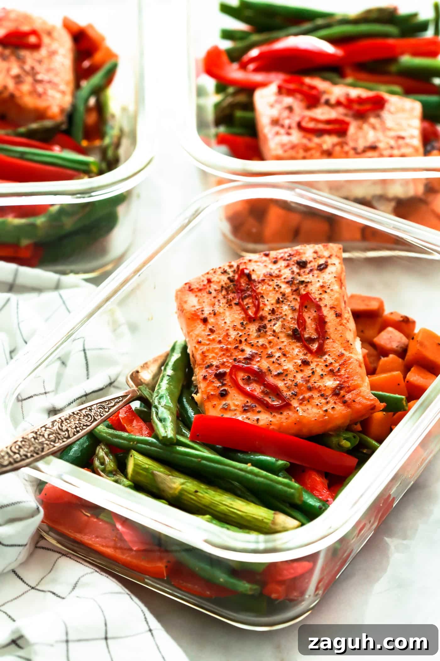 15 Whole30 Meal-Prep Recipes for Stress-Free Weekly Planning 4 A glass meal prep container with a piece of spicy salmon over roasted veggies.