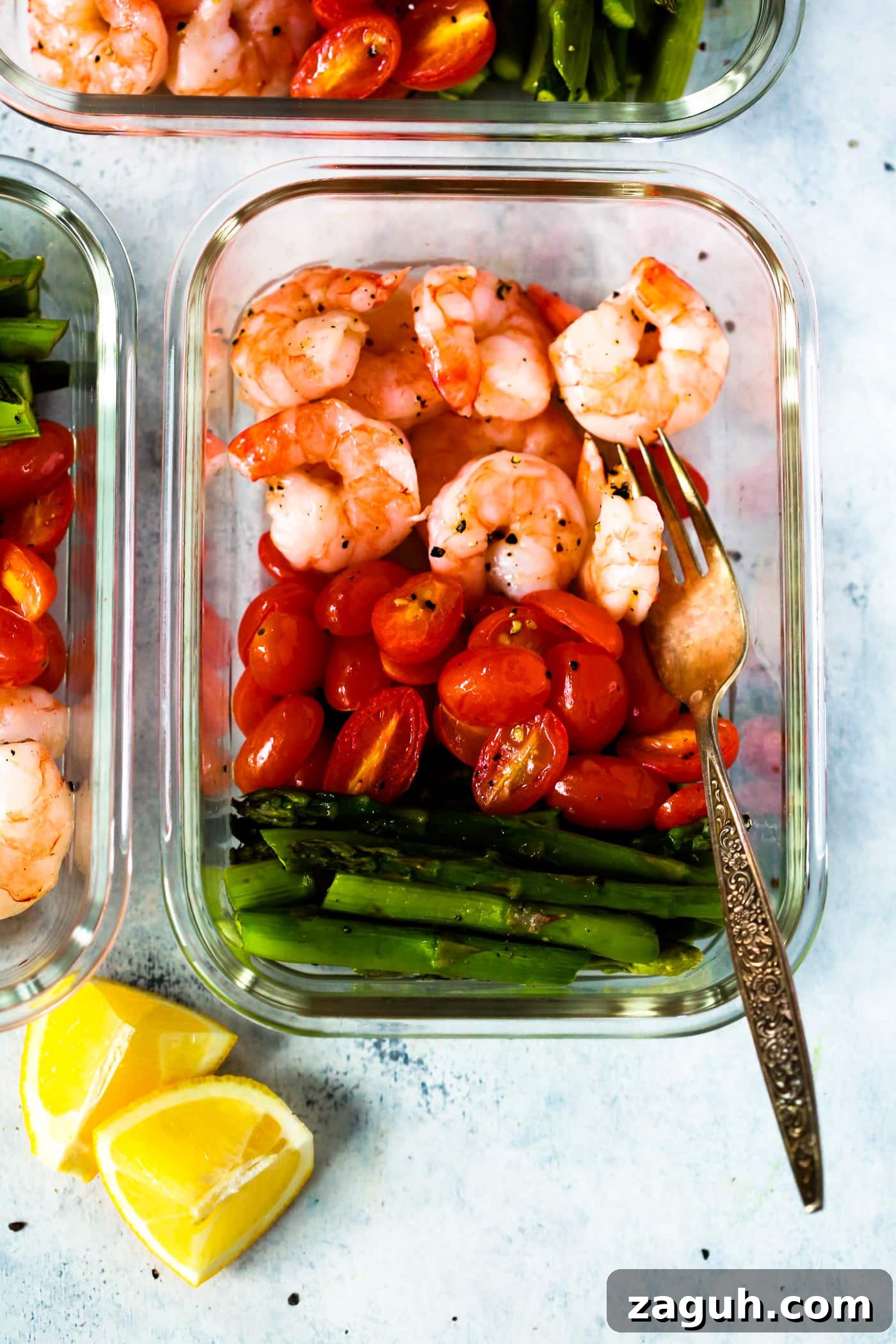 15 Whole30 Meal-Prep Recipes for Stress-Free Weekly Planning 6 Meal prep containers full of shrimp, tomatoes, and asparagus with a fork on the side.