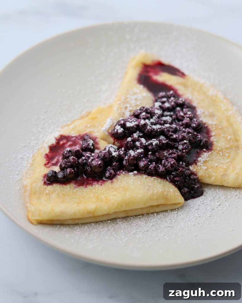 Swedish Pancakes with Vanilla Pastry Cream & Blueberry-Cardamom Compote 4 Swedish pancakes on a plate with blueberry compote