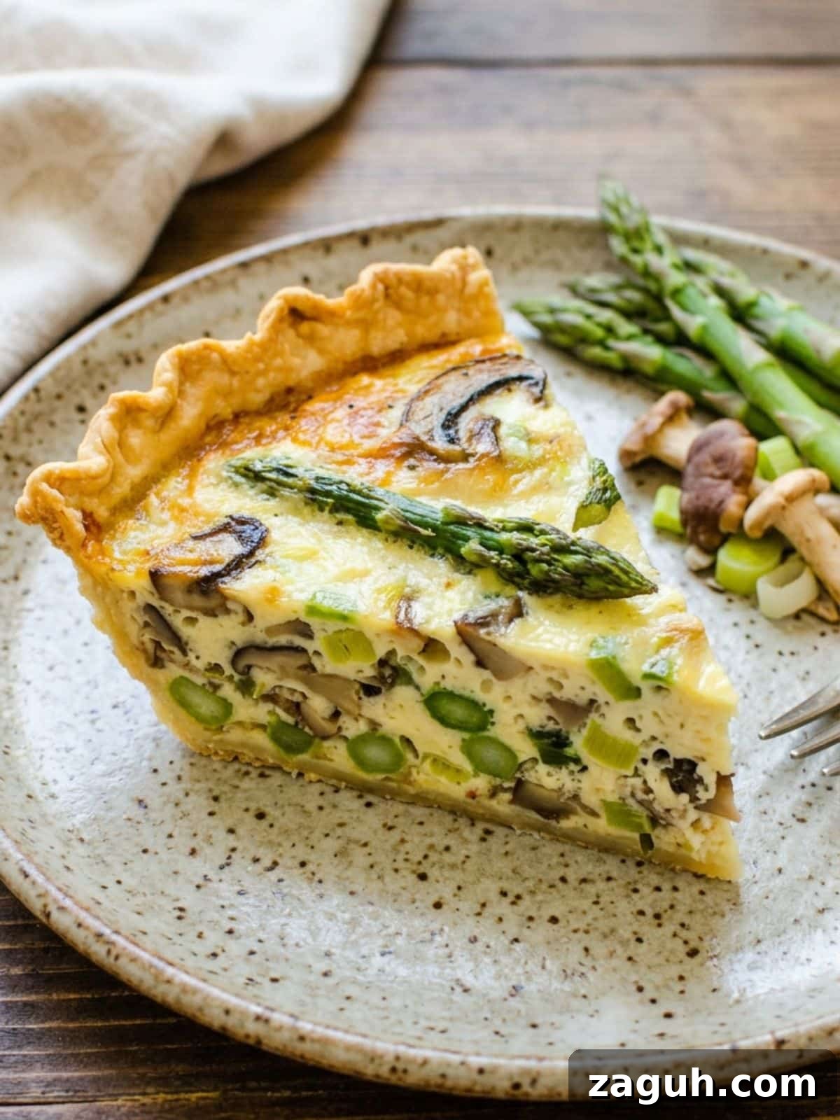 Asparagus, Mushroom & Gruyère Quiche with Leeks for Spring Brunch 8 A slice of the quiche on a plate.