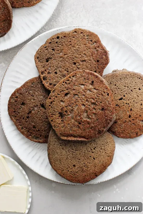 Whip up a batch of these fluffy vegan buckwheat pancakes for a delicious healthy breakfast! Easy, tender and filled with a touch of warm cinnamon, these from scratch gluten free pancakes are hard to beat! A white plate filled with Healthy Buckwheat Pancakes.