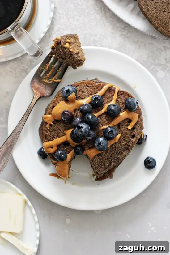 These light and fluffy healthy buckwheat pancakes are hard to beat! Easy to make, healthy and filled with just the right touch of warm cinnamon. And they reheat beautifully making them perfect for busy mornings. Vegan and gluten free! Gluten Free Buckwheat Pancakes on a plate topped with peanut butter and berries.