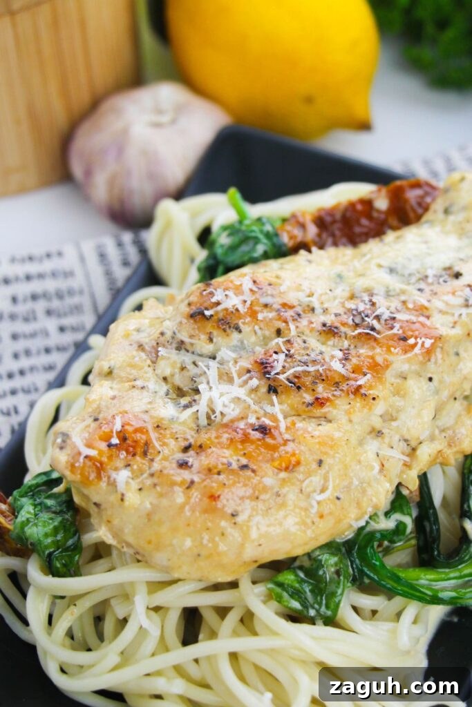 Tuscan-Style Creamy Garlic Chicken with Sun-Dried Tomatoes 11 chicken tuscany sitting on top a bed of spaghetti noodles on table