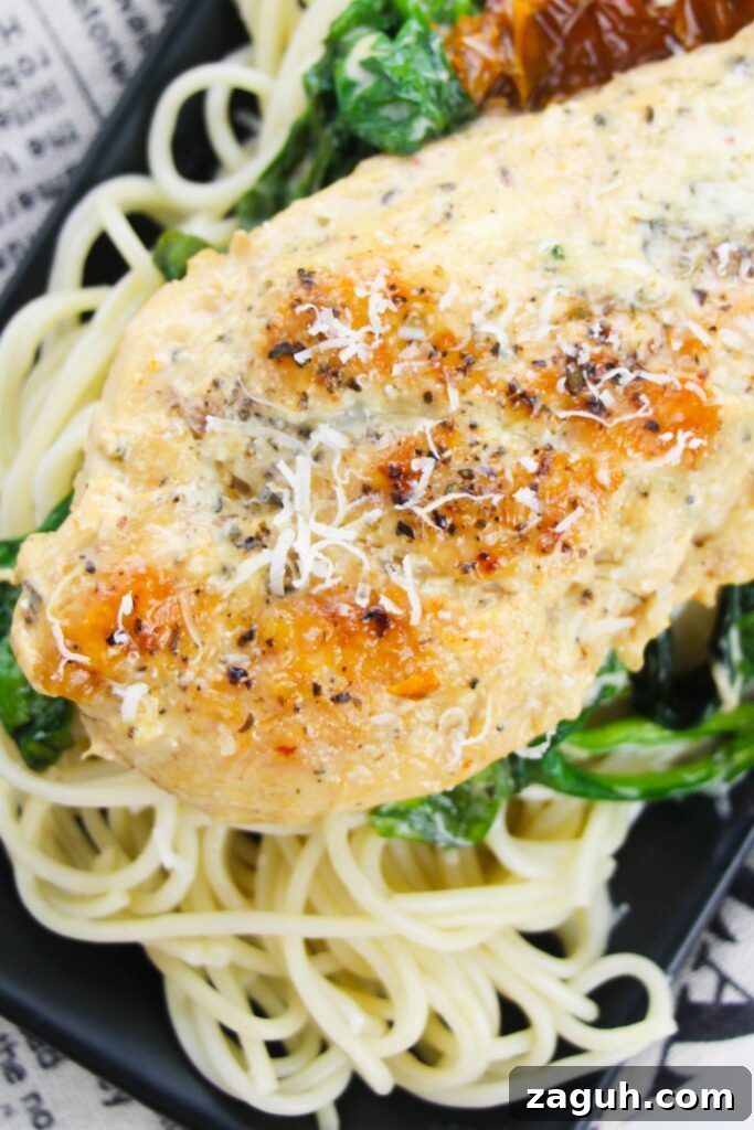 Tuscan-Style Creamy Garlic Chicken with Sun-Dried Tomatoes 13 close up of seared chicken with parmesan cheese on top sitting on a plate on table