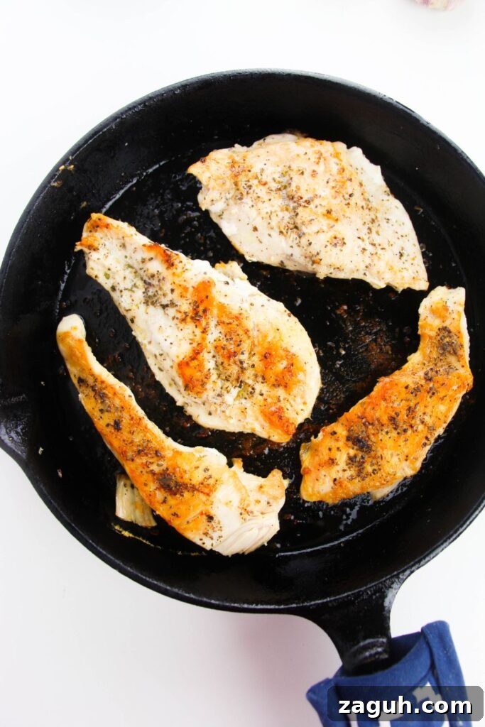 Tuscan-Style Creamy Garlic Chicken with Sun-Dried Tomatoes 5 seared chicken in a cast iron skillet siting on a white table