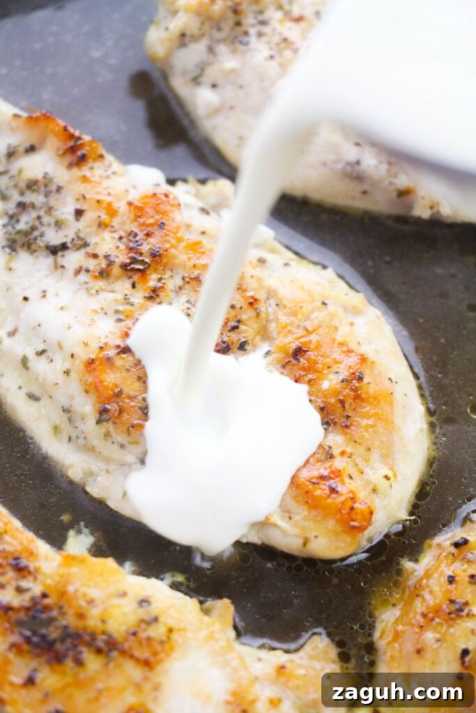 Tuscan-Style Creamy Garlic Chicken with Sun-Dried Tomatoes 7 pouring heavy cream into a pan with seared chicken and chicken broth in it