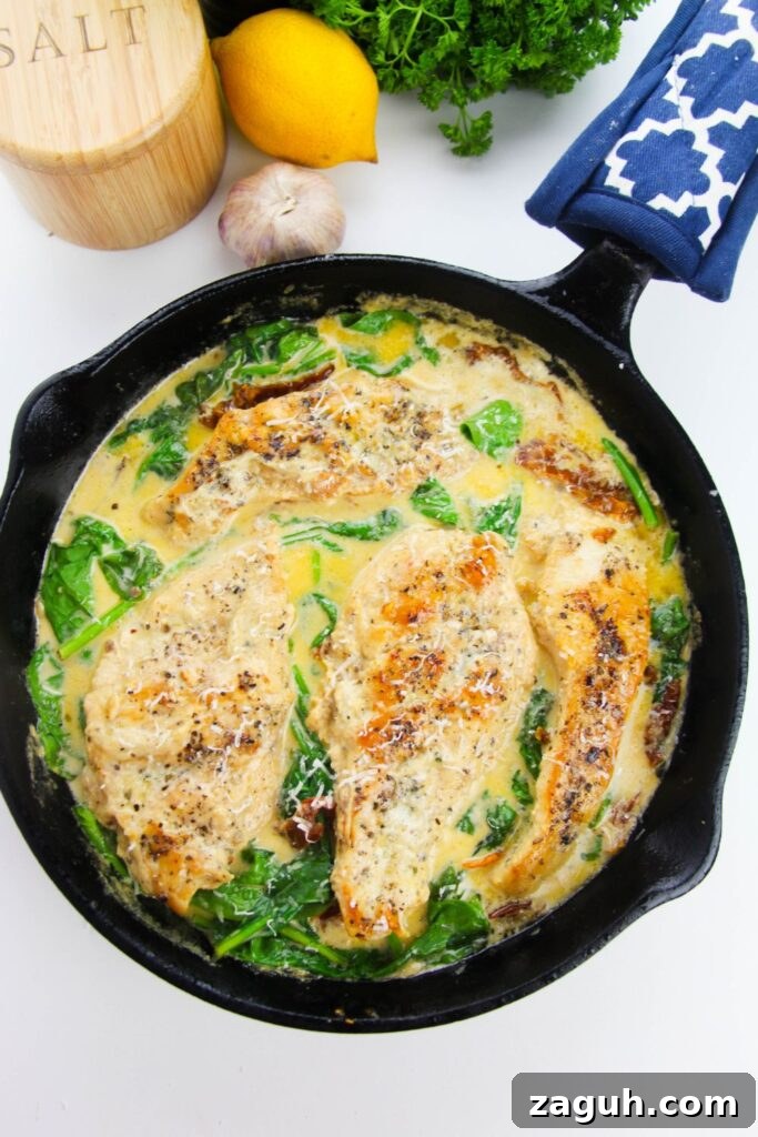Tuscan-Style Creamy Garlic Chicken with Sun-Dried Tomatoes 10 chicken Tuscan in pan on table with fresh herbs, lemon, garlic and salt sitting by the pan