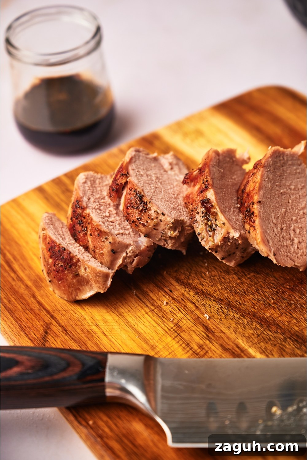 Juicy Sous Vide Pork Tenderloin Recipe — Perfectly Cooked Every Time 2 Close up of sliced cooked pork tenderloin atop a wood cutting board.